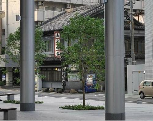 a building with a tree in the middle of a street at Yamamoto Ryokan in Fukuoka