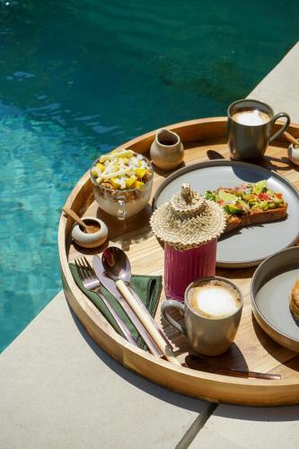 a tray of food on a table next to a pool at Kalyana Villa Gili Air in Gili Air