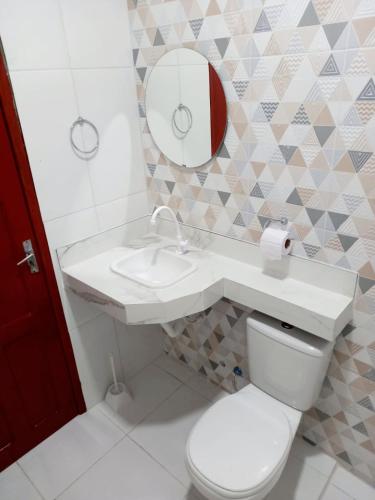 ein Badezimmer mit einem WC, einem Waschbecken und einem Spiegel in der Unterkunft Apartamento Aconchegante in Boa Vista
