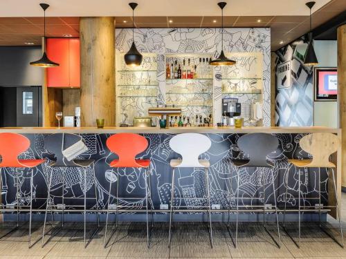 a bar with red stools in front of a wall covered in graffiti at ibis Hotel Hannover City in Hannover