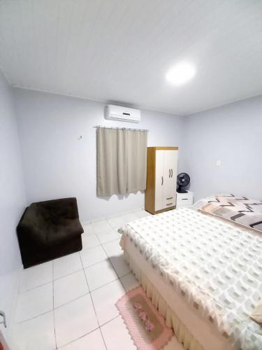ein weißes Schlafzimmer mit einem Bett und einem Stuhl in der Unterkunft Apartamento Aconchegante in Boa Vista