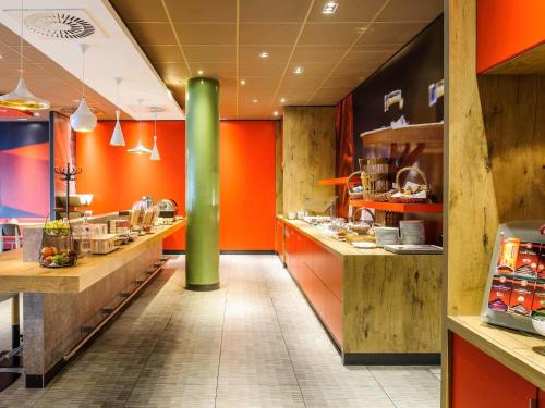 a large kitchen with orange walls and a green pole at ibis Hotel Hannover City in Hannover