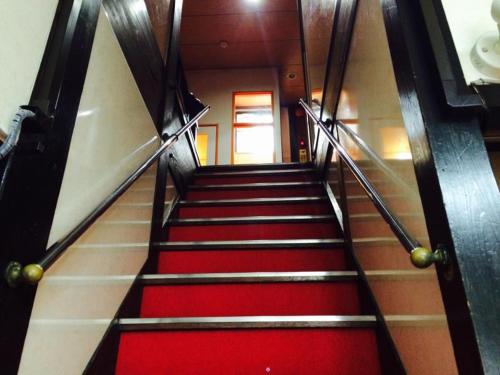 a staircase in a building with red carpeted stairs at Yamamoto Ryokan in Fukuoka