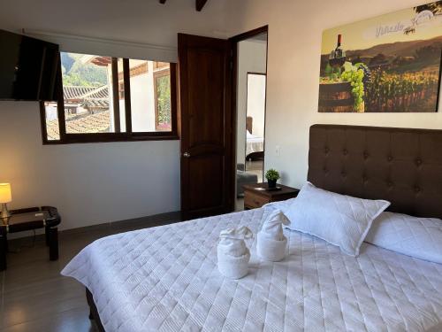 a bedroom with a large white bed with two pillows at Casa Hotel El Encanto de Villa in Villa de Leyva