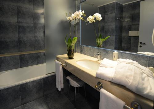 a bathroom with a sink and a mirror and flowers at Hotel Mamiani & Relaxing Spa Urbino in Urbino