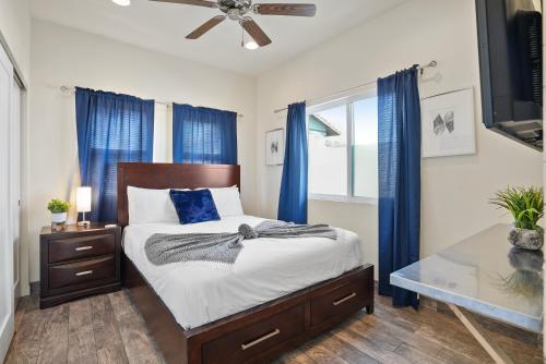 a bedroom with a bed with blue curtains and a ceiling fan at Ocean View Paradise w Private Patio & Spa in San Diego