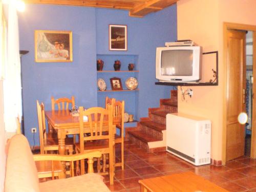 a dining room with a dining table and a television at Los Olmos Holiday Home in Fuentidueña