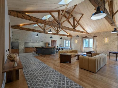 Cette grande chambre est dotée de plafonds en bois, de tables et de chaises. dans l'établissement Loft lumineux avec cuisine équipée et circuits truffes - Centre-ville Jarnac - FR-1-653-248, à Jarnac