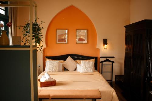 a bedroom with a large bed with an orange wall at Alsahar Hoi An Boutique Villa in Hoi An
