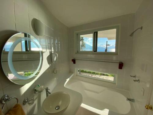 Baño blanco con lavabo y espejo en Villa Palopo en Santa Catarina Palopó