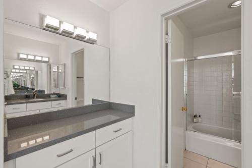 a white bathroom with a sink and a mirror at Belmont Modern - Ocean View, Pet Friendly, Patio in San Diego