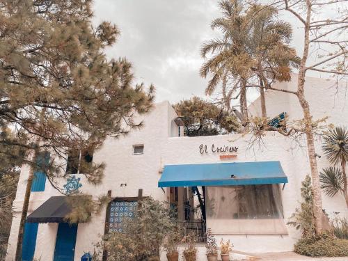 a white building with a blue awning and trees at La bella tagaytay- Casa Raffa in Tagaytay