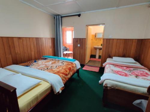 a small room with two beds and a mirror at Carnation Rest in Nuwara Eliya