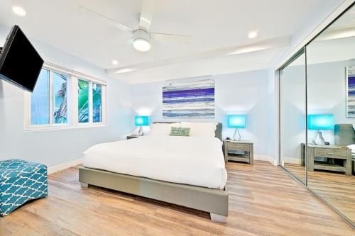 a white bedroom with a bed and a flat screen tv at Stunning South Mission Home with Private Rooftop & Ocean Views! in San Diego