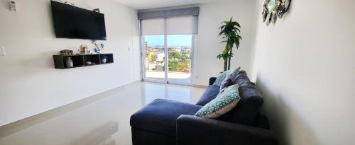 a living room with a blue couch and a tv at Torre Alba 103 in Mazatlán