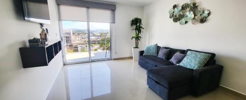 a living room with a couch and a chair and a window at Torre Alba 103 in Mazatlán