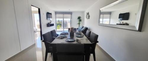 a dining room with a long table with black chairs at Torre Alba 103 in Mazatlán