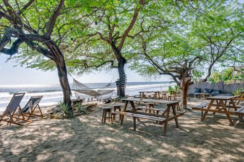 um grupo de mesas de piquenique e cadeiras na praia em Popoyo Republic em Popoyo