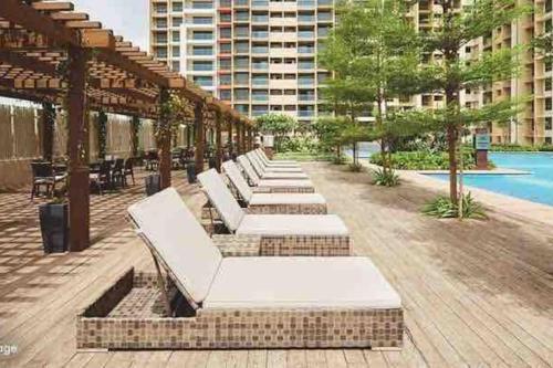 a row of white chaise lounges on a patio at 1-BHK:Where Comfort Meets luxury in Mumbai