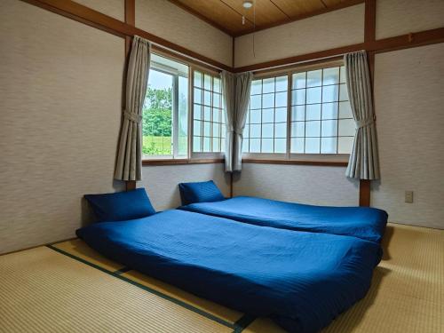 a bedroom with a blue bed in a room with windows at Biei Snow House - Vacation STAY 14827 in Biei
