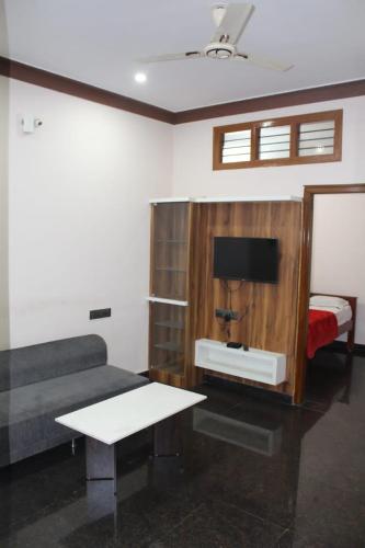 a living room with a couch and a tv and a table at Regency apartment in Mysore