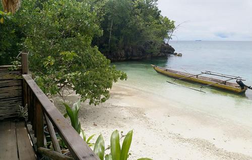 a boat sitting on a beach next to the ocean at Marwes Homestay in Selebam
