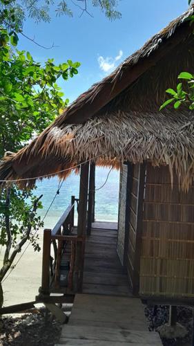 a straw hut with a staircase leading to the beach at Marwes Homestay in Selebam