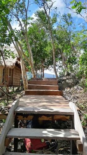 a set of wooden stairs with trees in the background at Marwes Homestay in Selebam