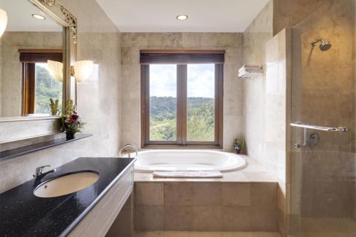 bagno con vasca, lavandino e finestra di Rijasa Agung Resort and Villas a Payangan