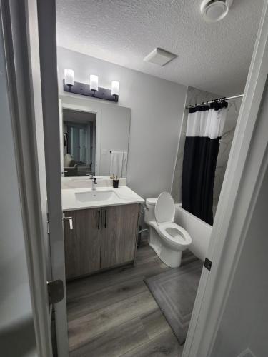 uma casa de banho com um lavatório, um WC e um espelho. em Home Away From Home em Edmonton