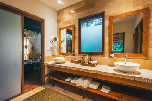 a bathroom with two sinks and two mirrors at El Silencio Lodge & Spa Costa Rica in Toro Amarillo