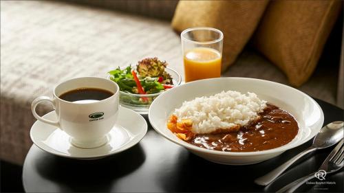 Daiwa Roynet Hotel Osaka Sakaisuji Honmachi PREMIER في أوساكا: طاولة مع وعاء من الأرز وكوب من القهوة