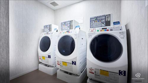 two washing machines are in a room with a wall at Daiwa Roynet Hotel Osaka Sakaisuji Honmachi PREMIER in Osaka