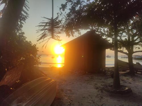 uma pequena cabana na praia com o pôr do sol em kitnets Porto Marujo em Paranaguá