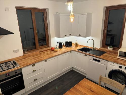 a kitchen with white cabinets and a wooden counter top at 3 Bed Ground Floor Apartment - Hot Tub Optional in Hythe