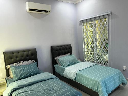 two beds sitting next to each other in a room at Freesia Haus in Kota Bharu