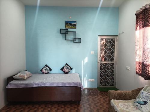 a bedroom with a bed with a blue wall at DHAULADHAR HOMESTAY PALAMPUR in Pālampur