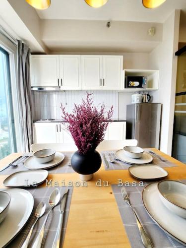 a kitchen with a table with plates and a vase of flowers at SMDC Wind: T2 La Maison du Basa in Tagaytay