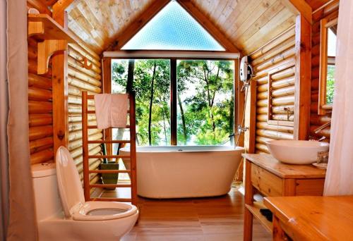 a bathroom with a toilet and a large window at Phu Ninh Lake Resort & Spa in Tam Ky