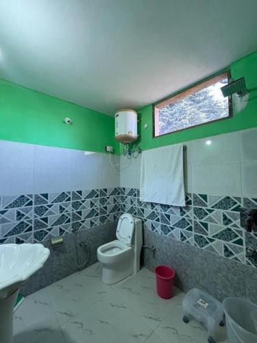 a bathroom with a toilet and a sink and a window at Pinehill cottage in Jibhi