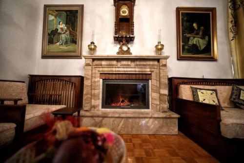 a living room with a fireplace and a clock and paintings at Κομψό & πολυτελές νεοκλασικό στο κέντρο της πόλης in Kastoria