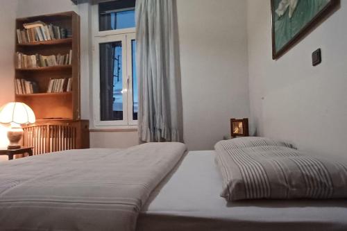 a white bedroom with a bed and a window at Κομψό & πολυτελές νεοκλασικό στο κέντρο της πόλης in Kastoria