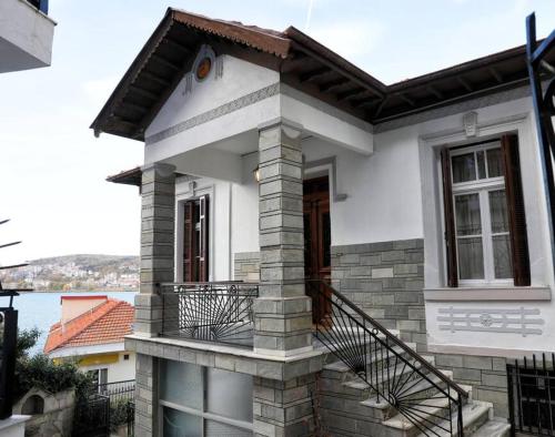 a white house with a balcony and a door at Κομψό & πολυτελές νεοκλασικό στο κέντρο της πόλης in Kastoria