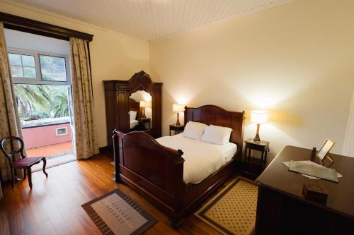 um quarto com uma cama, uma secretária e uma janela em Solar de Lalém em Maia