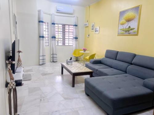 a living room with a blue couch and a table at Leisure Homestay in Kampong Peruntun