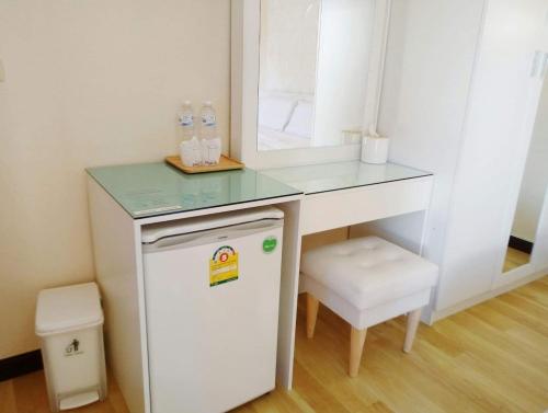 a small white desk with a mirror and a small refrigerator at โรงแรมเรือนไทย 1 (Thai Guest House) in Ban Don Klang