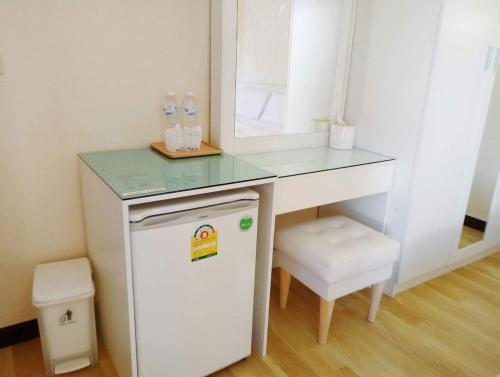 a small white desk with a mirror and a small refrigerator at เรือนไทย 1 in Ban Don Klang