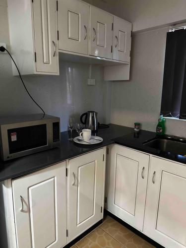 a kitchen with white cabinets and a microwave at Home Away Comfort stay in Suva