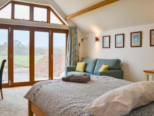 een slaapkamer met een bed, een bank en een raam bij Lower Netherdowns in Littleham