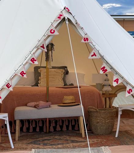 a bed in a tent with a table in front at Foxton Beach Holiday Park in Foxton Beach
